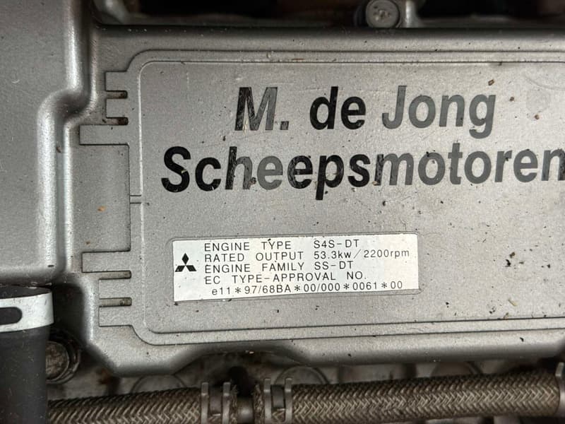 Een close-up van een metalen plaat met de tekst "M. de Jong Scheepsmotoren" en specificaties van een motor.