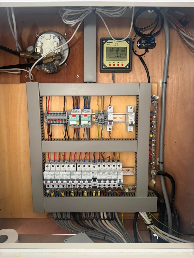 Een gedetailleerde foto van een elektrisch paneel met zekeringen, bedrading en een digitale meter.