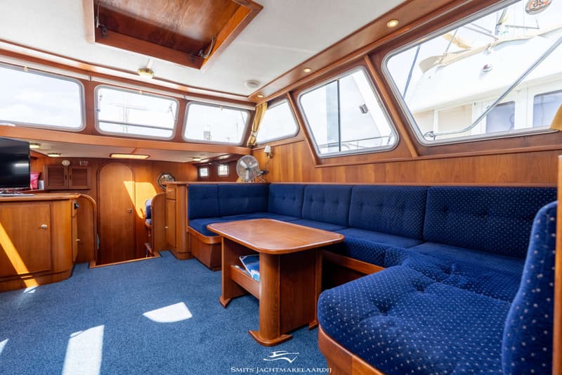De kajuit toont een blauw tapijt, houten wanden, een blauwe bank en een houten tafel. — Babro yachting Babro Classic 13.40 AK