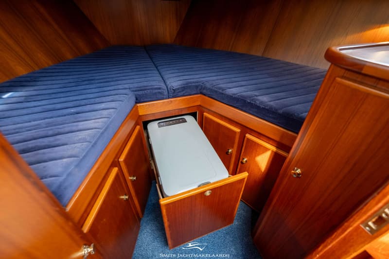Een kajuit met twee blauwe matrassen en een grijze koelbox in een houten kast. — Babro yachting Babro Classic 13.40 AK