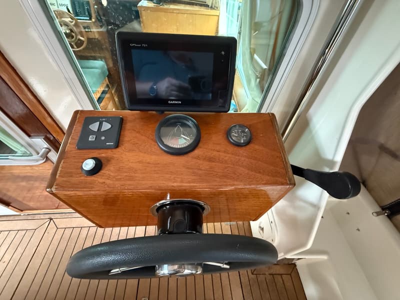 Een stuurstand met een zwart stuurwiel, een Garmin GPSmap 721, een kompas en een temperatuurmeter.