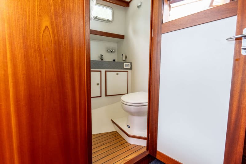 Een badkamer met een toilet, wastafel en houten vloer, gezien door een deuropening.