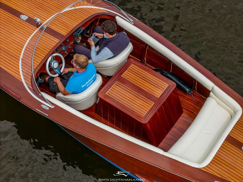 Een bovenaanzicht van een houten boot met twee mannen aan boord, waarvan één aan het stuur zit. — Divank Divank Uscire 635