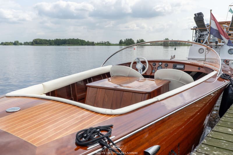 Een houten motorboot met een wit stuur en beige bekleding ligt aangemeerd aan een houten steiger. — Divank Divank Uscire 635