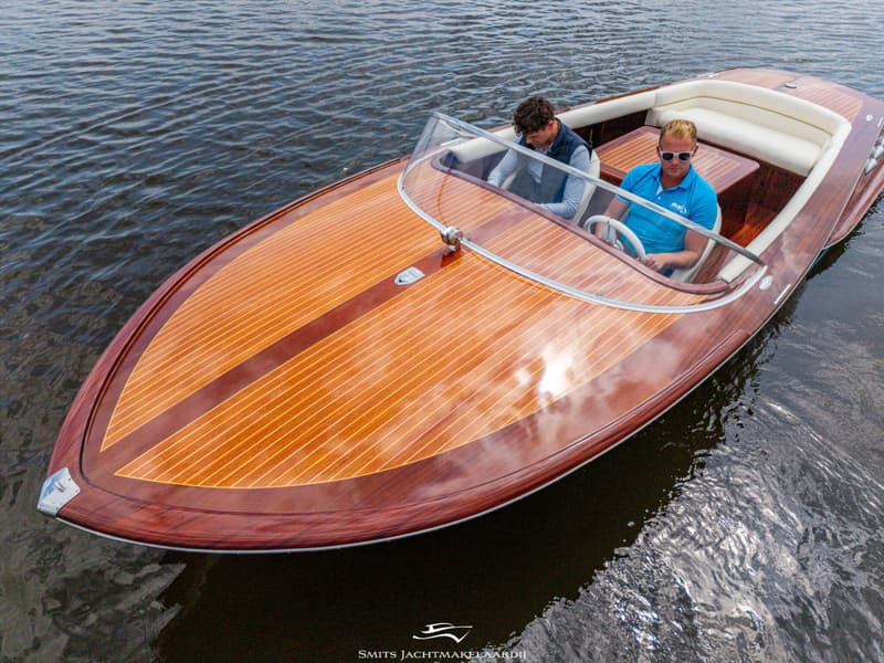 Een houten speedboot met twee mannen aan boord vaart op kalm water. — Divank Divank Uscire 635