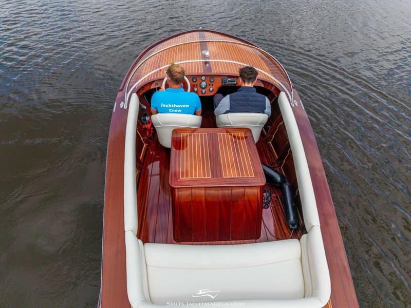 Twee mannen zitten in een houten boot met witte bekleding, varend op donker water. — Divank Divank Uscire 635