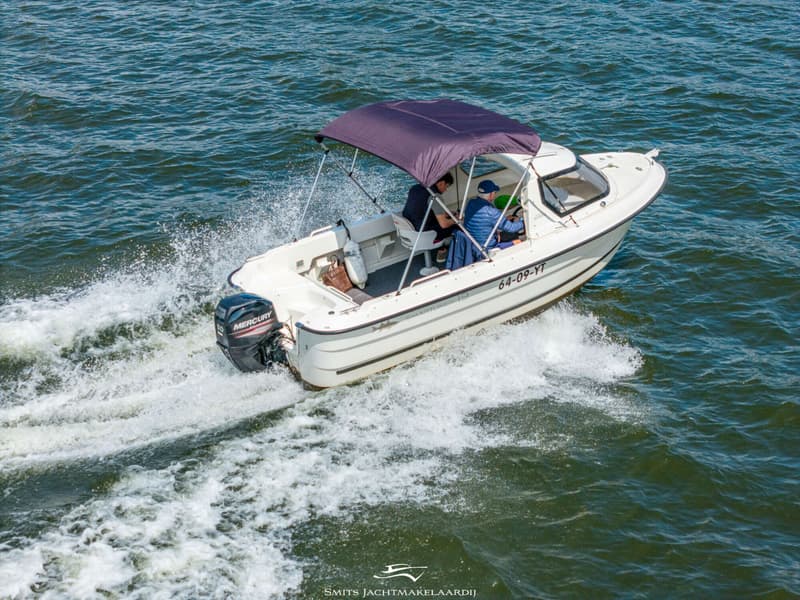 Een witte motorboot met twee opvarenden en een donkerblauwe biminitop vaart over het water. — Smartliner Smartliner 19 Cuddy
