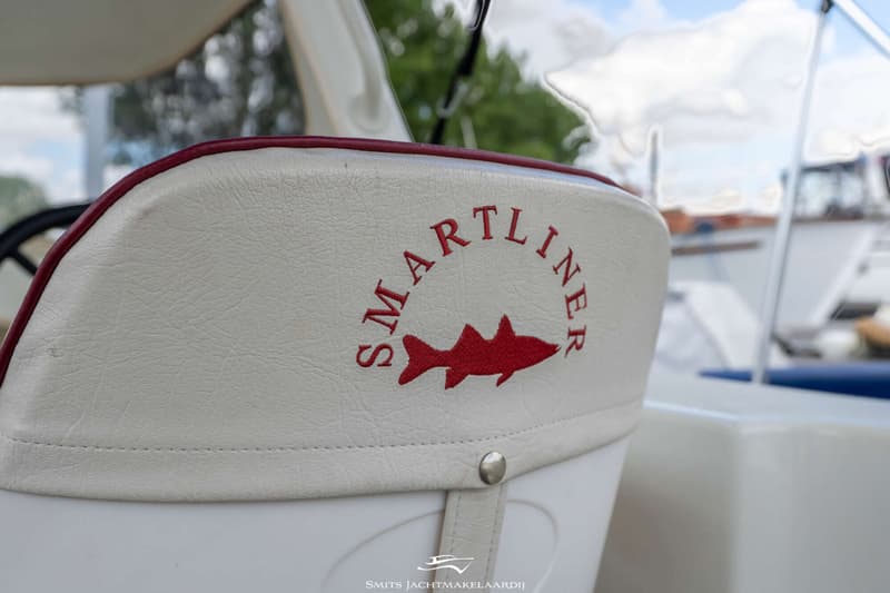 Een witte bootstoel met rode bies en een rood geborduurd logo van een haai en de tekst "SMARTLINER".