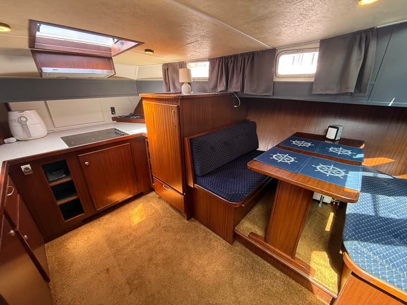 De foto toont een interieur van een boot met een kombuis, een eethoek en een tapijt op de vloer.