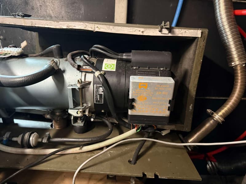 Een detailfoto van een Webasto-brander met bedrading, slangen en een Steuergerät (regelapparaat).