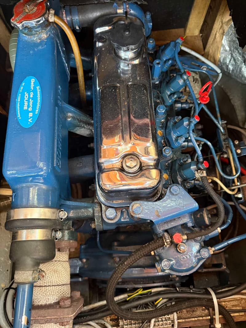 Een close-up van een blauwe scheepsmotor met chromen onderdelen en diverse leidingen en kabels.