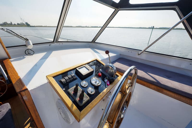 De foto toont het stuurwiel en het dashboard van een boot, met uitzicht op water en de horizon. — Valkkruiser 10.50 Ak Cabrio