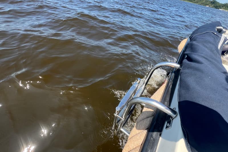Een roestvrijstalen zwemtrap met twee treden hangt aan de zijkant van een boot in het water. — Interboat 19
