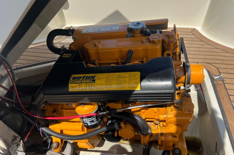Een Vetus Diesel M3.09 motor met een zwart deksel en gele onderdelen is zichtbaar.
