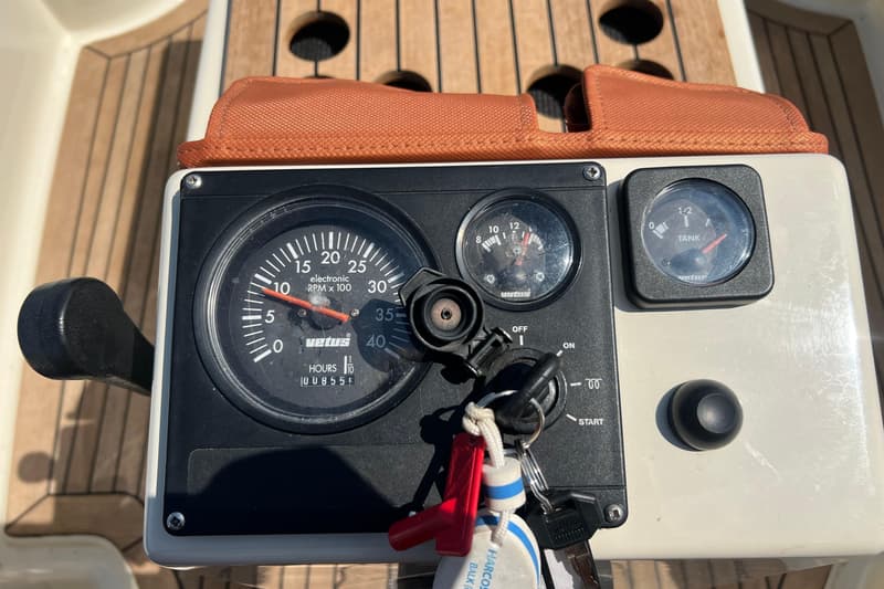 Een detailfoto van een dashboard met een toerenteller, een voltmeter en een brandstofmeter, met sleutels in het contact.