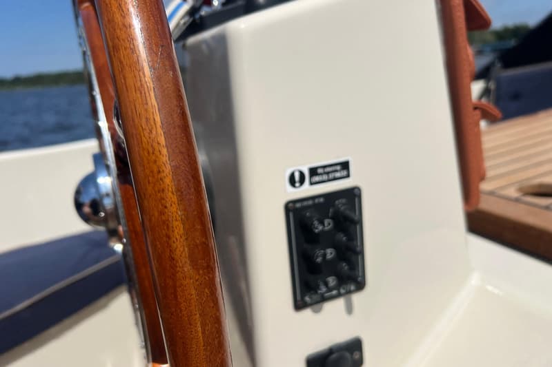 Een close-up van een houten stuurwiel en een bedieningspaneel met schakelaars op een boot. — Interboat 19