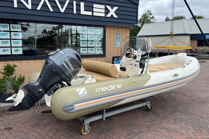 Een Zodiac Medline rubberboot met een Yamaha buitenboordmotor staat op een trailer voor een gebouw met de tekst "NAVILEX".