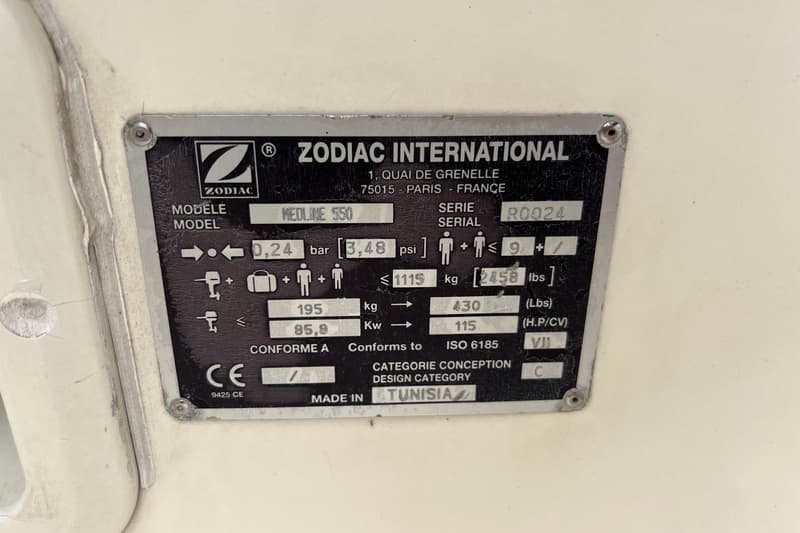 Een metalen plaatje met de tekst "ZODIAC INTERNATIONAL" en specificaties van een bootmodel "MEDLINE 550".
