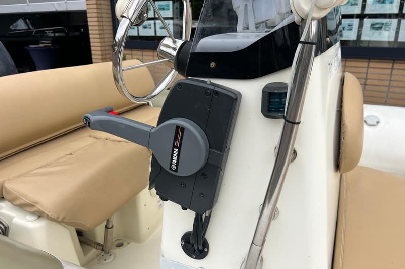 Een Yamaha afstandsbediening voor de motor is gemonteerd op een wit console, met een stuurwiel en beige bekleding.