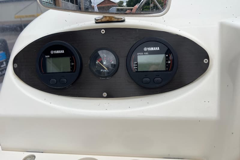 Een wit dashboard met een donkergrijs paneel waarop drie meters zijn gemonteerd, waaronder twee Yamaha-meters en een…