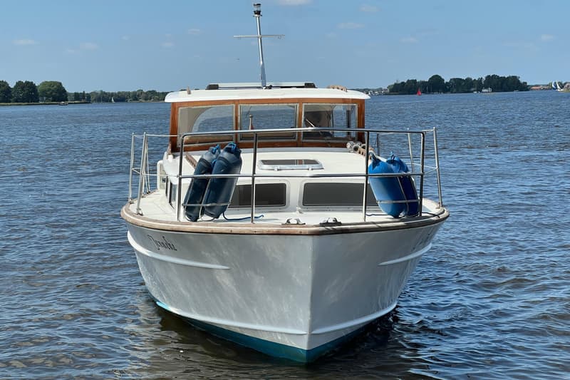 Een witte motorboot met houten details en de naam "Jendine" op de boeg, drijft op het water. — Kruiser Polyflash 950