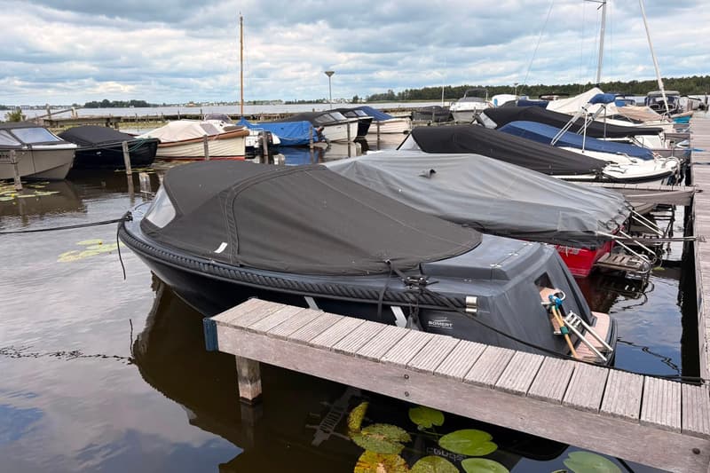 Een jachthaven met meerdere boten, de meeste afgedekt met zeilen, onder een bewolkte hemel.