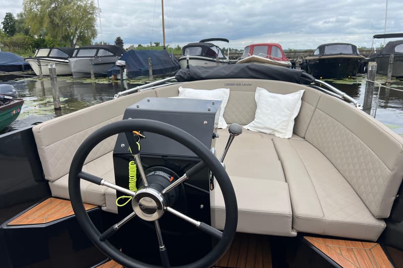 Een boot met een zwart stuur en beige bekleding, met op de achtergrond andere boten in het water. — Corsiva 500 Tender