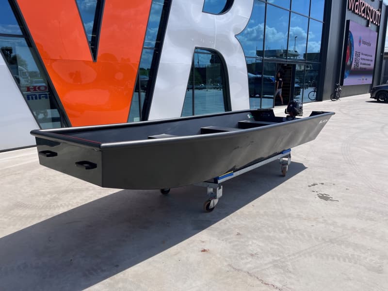 Een zwarte boot met een buitenboordmotor staat op een trailer voor een gebouw met glazen — Black work boats Black Jon 500