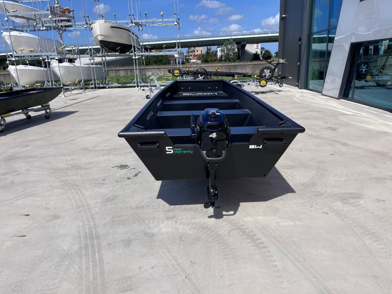 Een zwarte boot met een buitenboordmotor staat op een betonnen ondergrond, met andere boten — Black work boats Black Jon 500