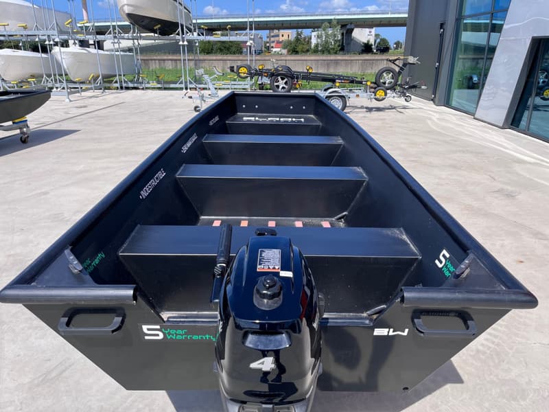 Een zwarte boot met een buitenboordmotor staat op een betonnen ondergrond, met andere boten — Black work boats Black Jon 500