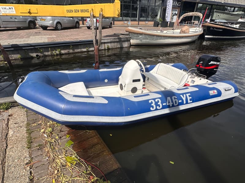 Een blauw-witte rubberboot met een buitenboordmotor en de registratie "33-46-YE" ligt in het water.