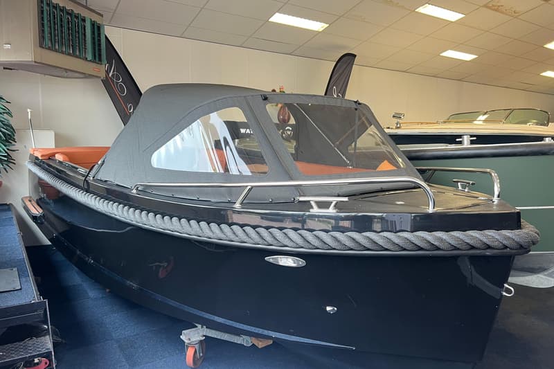 Een zwarte sloep met een grijs touw als stootrand en een donkergrijze buiskap met doorzichtige ramen. — Lago Amore 606 Tender
